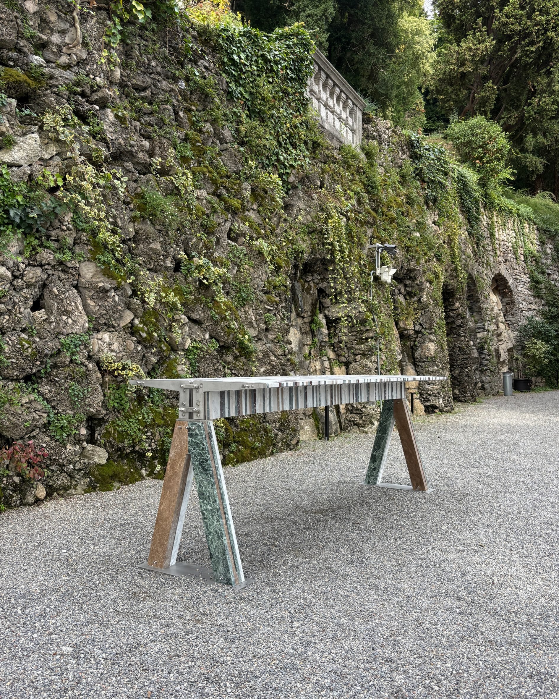 Table made from marble fragments and stainless steel brackets on an outdoor gravel area