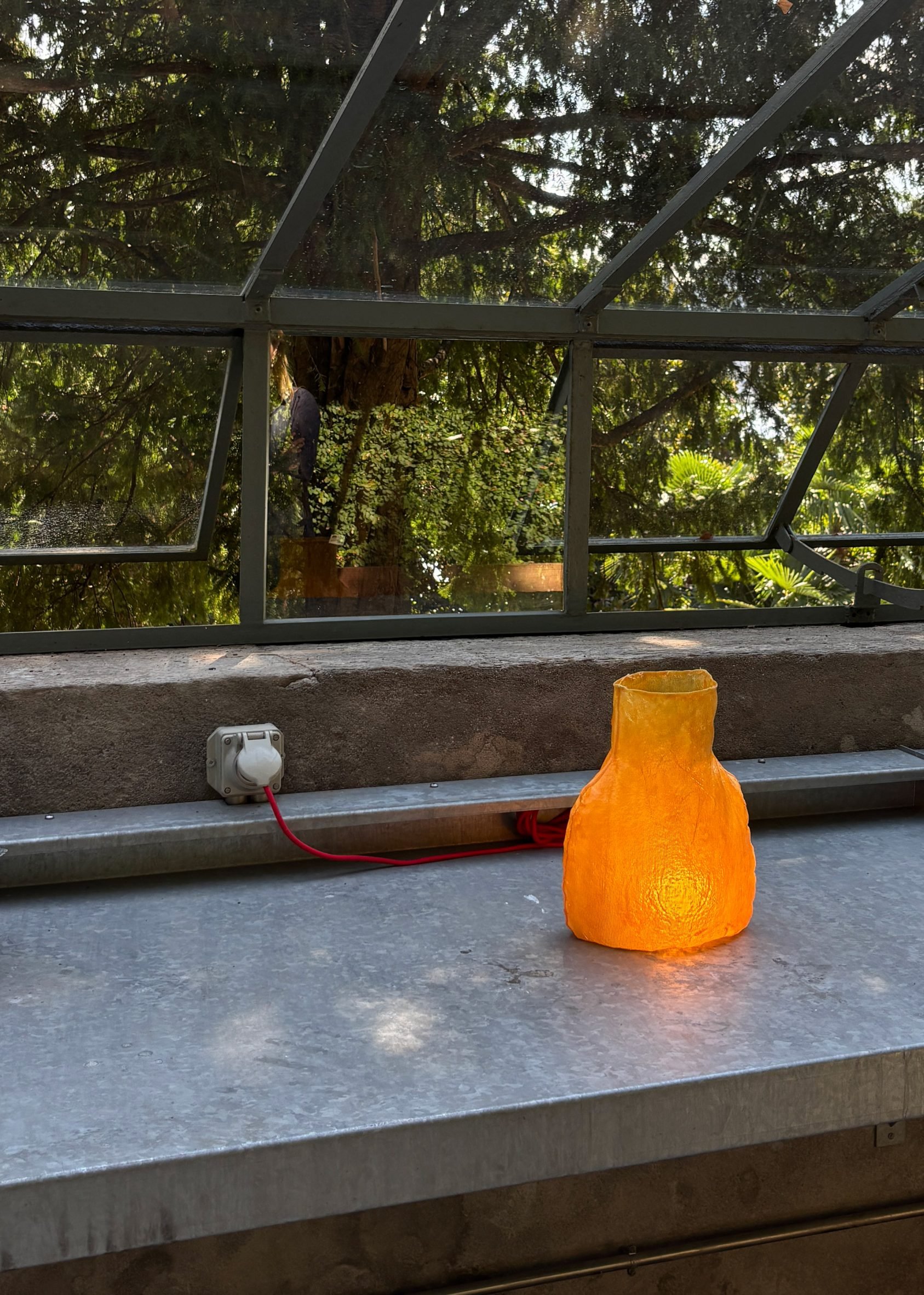 Orange lamp with red cord in greenhouse